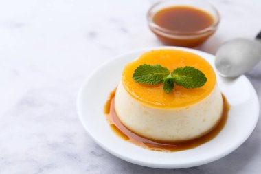 Beyaz mermer masada servis edilen karamelli puding, yakın plan. Metin için boşluk