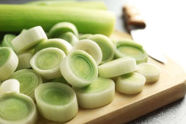 Gri masada doğranmış pırasa ve bıçak, yakın plan.