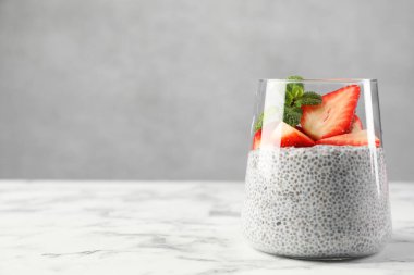 Çilekli lezzetli chia pudingi ve beyaz mermer masada nane şekeri.
