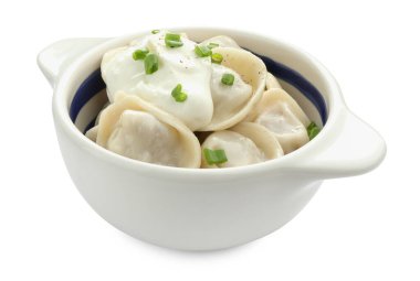 Lezzetli hamur köfteleri (pelmeni) yeşil soğanlı ve ekşi kremalı beyaz tencereye izole edilmiş.