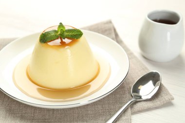 Karamel soslu lezzetli puding ve beyaz masada servis edilen nane şekeri.