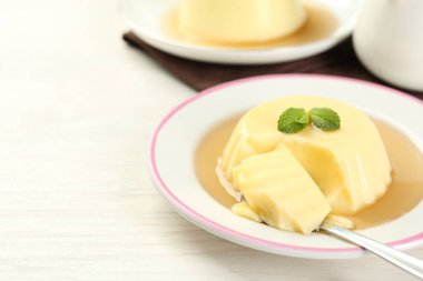 Karamel soslu lezzetli puding ve beyaz masada servis edilen nane. Metin için boşluk
