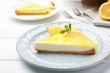 Beyaz ahşap masada servis edilen limonlu peynirli kek, yakın plan.