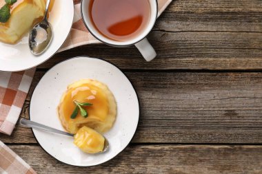 Delicious pudding with caramel sauce and mint served on wooden table, flat lay. Space for text