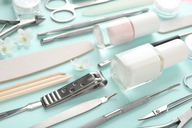 Turkuaz arka planda farklı manikür araçları ve çiçekler, yakın plan