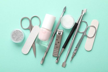 Turkuaz zemin üzerinde farklı manikür araçları kümesi, düz yatar