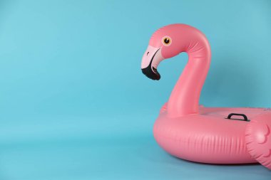 Açık mavi arkaplanda şişirilebilir flamingo şekilli halka, metin için boşluk