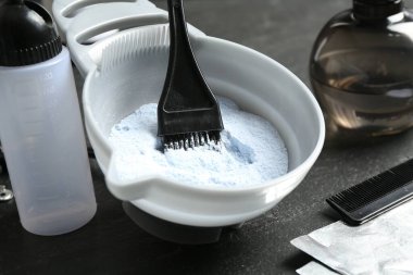 Beyazlatma tozu ve kuaför aletleri gri masada, yakın plan.