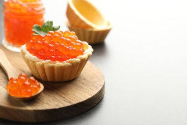 Kırmızı havyarlı kanepe, gri masada kaşık ve maydanoz, yakın plan. Metin için boşluk