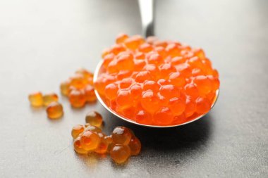 Gri masada kaşıkta lezzetli kırmızı havyar, yakın plan.