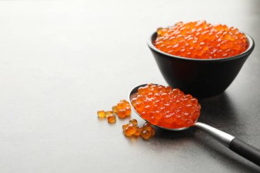 Lezzetli kırmızı havyar kasede ve kaşık gri masada, yakın plan. Metin için boşluk