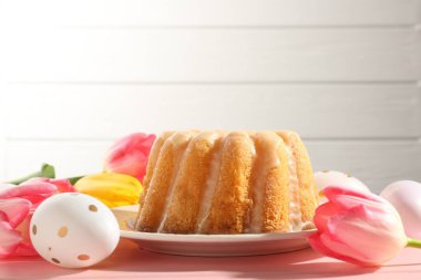 Lezzetli kek, Paskalya yumurtası ve laleler pembe ahşap masada, yakın plan.