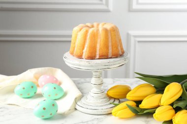 Lezzetli kek, Paskalya yumurtası ve beyaz mermer masada laleler.