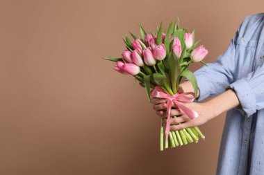 Koyu bej arka planda bir buket güzel lalesi olan kadın, yakın plan. Metin için boşluk