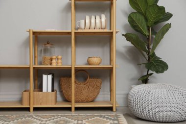 Açık gri duvarın yanında farklı dekorasyona sahip ahşap raf ünitesi.