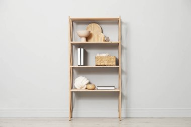 Açık gri duvarın yanında farklı dekorasyona sahip ahşap raf ünitesi.