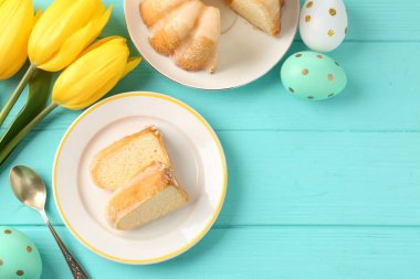 Lezzetli kek parçaları, paskalya yumurtaları ve laleler açık mavi ahşap masa, düz yatıyordu.