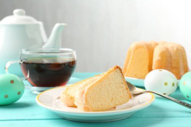 Lezzetli kek parçaları, Paskalya yumurtası ve açık mavi ahşap masa üzerinde çay.