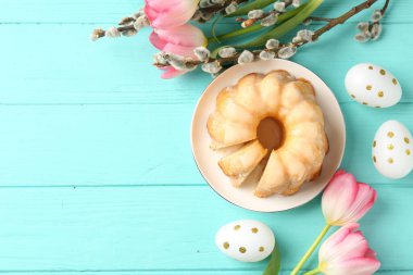 Lezzetli kek, Paskalya yumurtası, söğüt dalları ve açık mavi ahşap masa üzerindeki laleler, düz yatak. Metin için boşluk