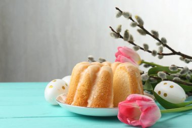 Lezzetli kek, Paskalya yumurtası, söğüt dalları ve açık mavi ahşap masada laleler.