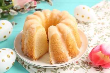 Lezzetli kek, Paskalya yumurtaları, söğüt dalları ve açık mavi masadaki laleler, yakın plan.