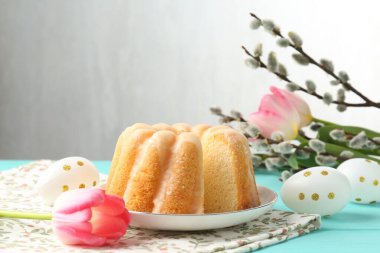 Lezzetli kek, Paskalya yumurtası, söğüt dalları ve açık mavi ahşap masada laleler.