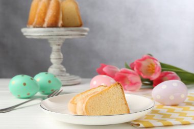 Lezzetli kek parçaları, beyaz ahşap masada paskalya yumurtaları ve laleler.