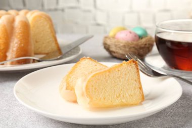 Lezzetli kek parçaları, paskalya yumurtası ve çay gri masada, yakın plan.