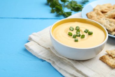 Lezzetli peynir sosu kaseye, krakerler açık mavi ahşap masaya, yakın plan. Metin için boşluk