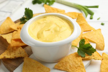 Peynir sosunu kaseye daldırmak ve cipsi masaya koymak, yakın plan.