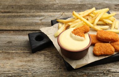Tabakta nefis peynir sosu, tavuk nugget ve ahşap masada patates kızartması, yakın plan. Metin için boşluk