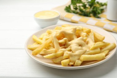 Peynir soslu patates kızartması ve beyaz ahşap masada maydanoz. Yakın plan.