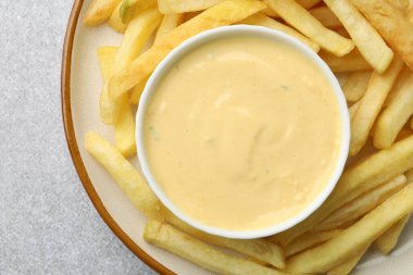 Lezzetli peynir sosu kasede ve patates kızartması gri masada.