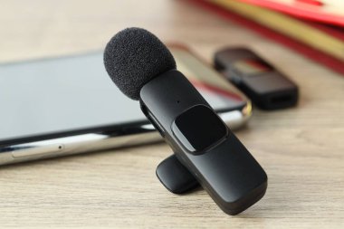 Lavalier mikrofon ve ahşap masada kablosuz alıcısı olan akıllı telefon.
