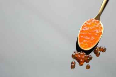 Gri ayna yüzeyinde kırmızı havyar, yakın plan. Metin için boşluk