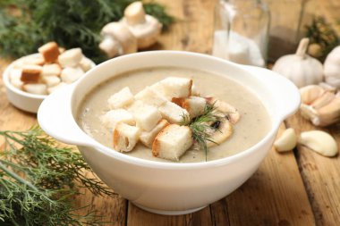 Lezzetli mantar kremalı çorba, kızarmış ekmek, dereotu ve ahşap masa malzemeleri, yakın plan.