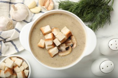 Lezzetli mantar kremalı çorba, beyaz mermer masa üzerinde kıtır ekmek ve malzemeler.