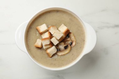 Lezzetli mantar kremalı çorba, beyaz mermer masa üzerinde kızarmış ekmek, üst manzara.