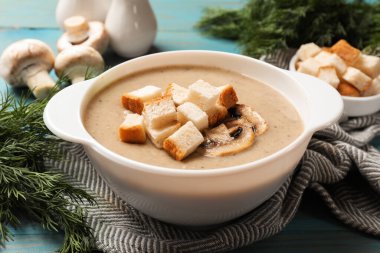 Lezzetli mantar kremalı çorba, kızarmış ekmek ve malzemeler mavi masada, yakın plan.