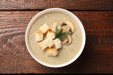 Lezzetli mantar kremalı çorba, kızarmış ekmek ve ahşap masa, üst manzara.