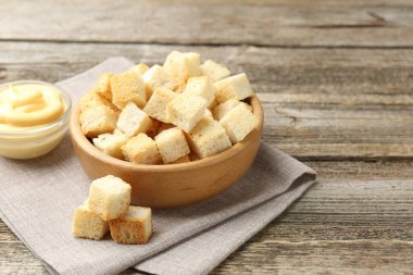 Tabakta çıtır çıtır ekmek ve ahşap masada sos, yakın plan.