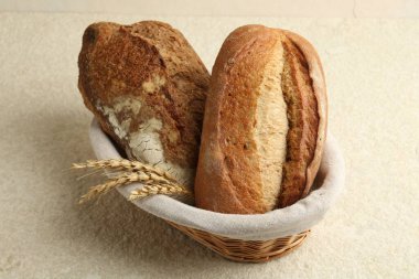 Hasır sepetin içinde farklı türde taze ekmek ve çiviler açık desenli masa üzerinde, yakın plan.