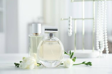 Parfüm şişeleri ve beyaz masada güzel çiçekler.