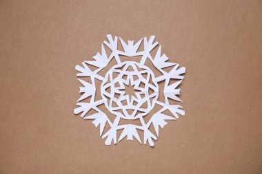 Kahverengi arka planda bir kağıt kar tanesi, üst manzara