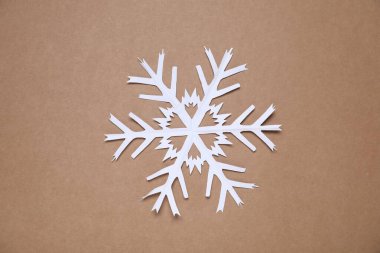 Kahverengi arka planda bir kağıt kar tanesi, üst manzara