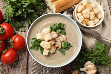 Lezzetli mantar kremalı çorba, kızarmış ekmek ve ahşap masadaki malzemeler.