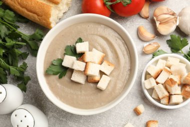 Lezzetli mantar kremalı çorba, kızarmış ekmek, maydanoz ve gri desenli masa, düz yatak.