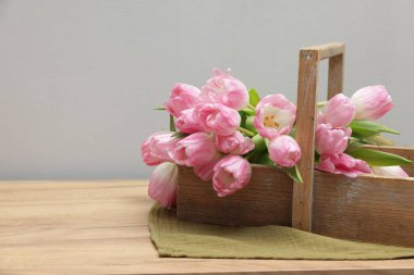 Güzel laleler sepetin içinde, ahşap masada, gri arka planda, yakın plan. Metin için boşluk