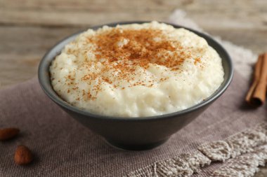 Tarçınlı lezzetli sütlaç ve ahşap masada badem, yakın plan.