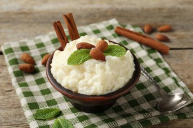 Tahta masada servis edilen bademli, nane ve tarçınlı lezzetli sütlaç, yakın plan.